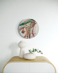 Abstract wall clock on a white wall above a wooden console table with decorative items.